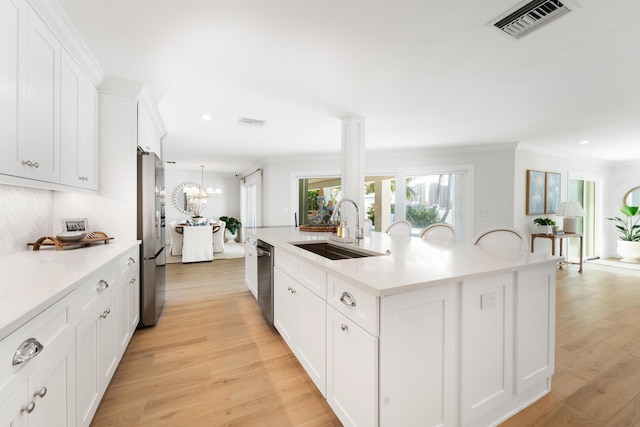 kitchen featuring sink, light hardwood / wood-style flooring, white cabinets, and a kitchen island with sink