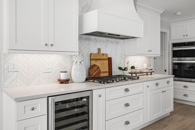 kitchen with stainless steel appliances, tasteful backsplash, beverage cooler, custom range hood, and white cabinets