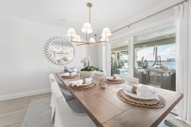 dining space featuring a chandelier, a water view, light hardwood / wood-style flooring, and ornamental molding