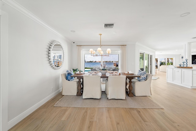 dining space with ornamental molding, an inviting chandelier, and light wood-type flooring