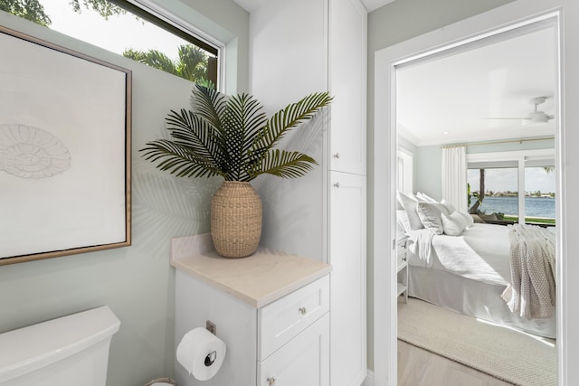 bathroom with toilet, ceiling fan, ornamental molding, and a water view