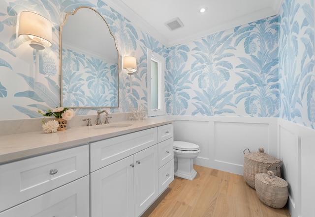 bathroom featuring toilet, vanity, ornamental molding, and hardwood / wood-style floors