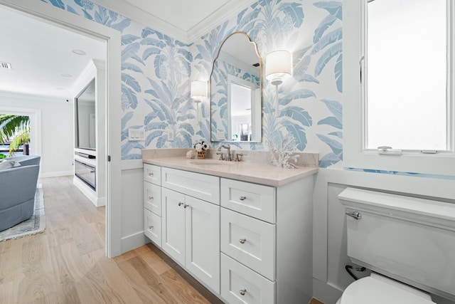 bathroom featuring toilet, ornamental molding, wood-type flooring, and vanity