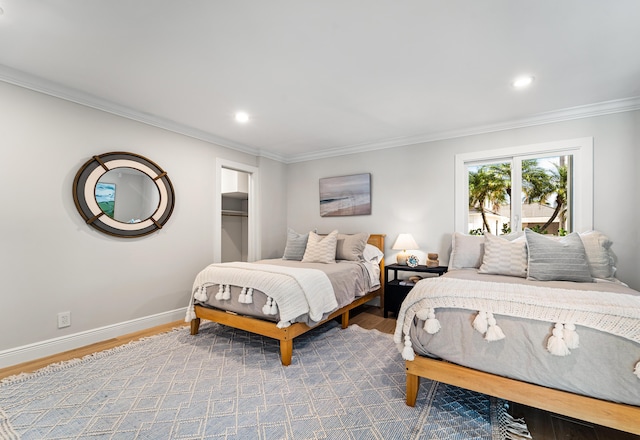 bedroom featuring hardwood / wood-style flooring, a walk in closet, and ornamental molding