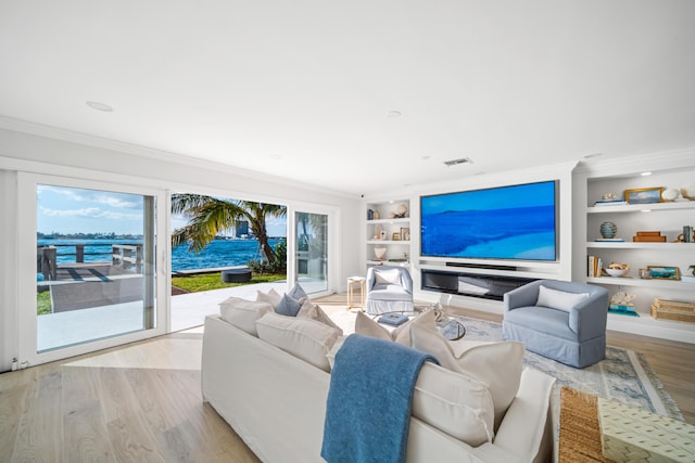 living room with light wood-type flooring, ornamental molding, built in features, and a water view