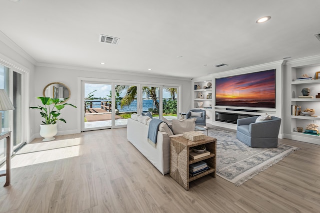 living room featuring built in features, ornamental molding, and light hardwood / wood-style flooring