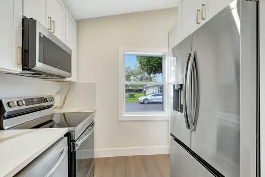 kitchen with white cabinets, hardwood / wood-style floors, and stainless steel appliances