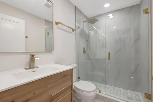 bathroom with vanity, toilet, and a shower with door