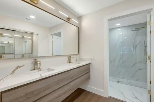 bathroom with hardwood / wood-style flooring, vanity, and a shower