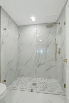 bathroom featuring toilet and a shower with shower door