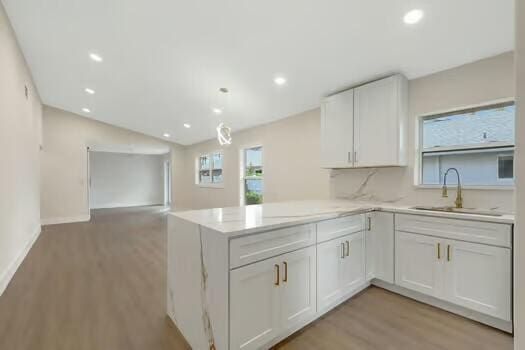 kitchen with white cabinetry, sink, backsplash, kitchen peninsula, and light hardwood / wood-style floors