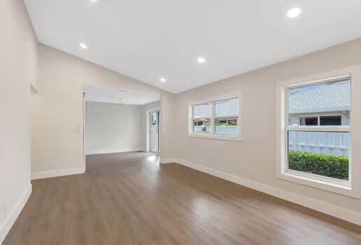 empty room with vaulted ceiling and dark wood-type flooring