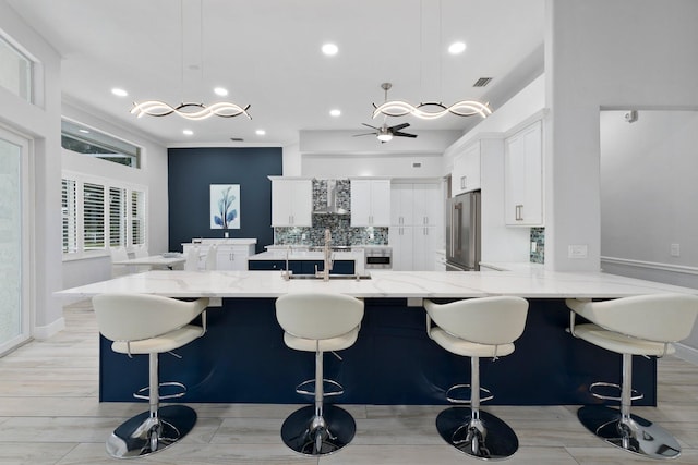 kitchen featuring high quality fridge, white cabinetry, light hardwood / wood-style flooring, and decorative light fixtures