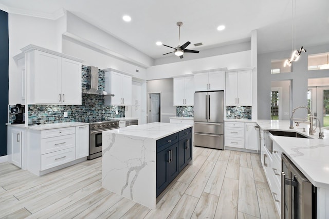 kitchen featuring decorative light fixtures, white cabinetry, appliances with stainless steel finishes, and wall chimney range hood