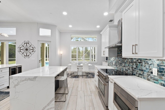 kitchen featuring white cabinetry, wine cooler, light stone counters, and stainless steel stove