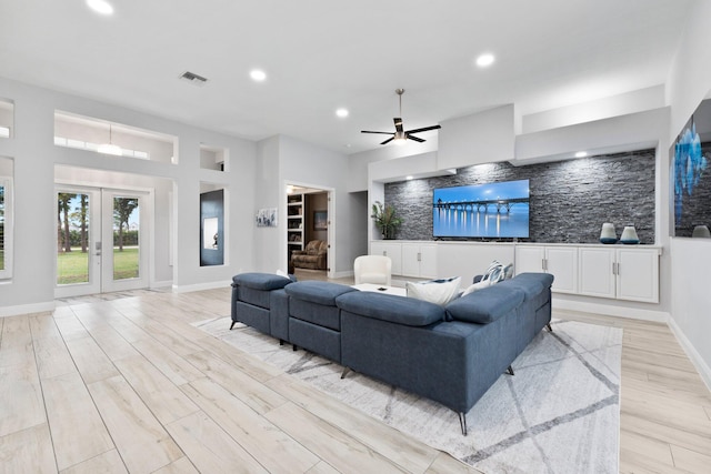 living room featuring french doors, light wood-type flooring, and ceiling fan