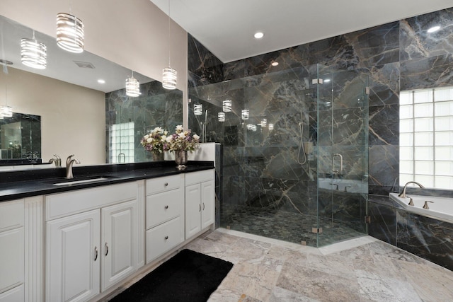 bathroom featuring plus walk in shower, vanity, and tile walls