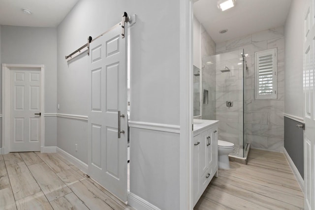 bathroom featuring hardwood / wood-style floors, vanity, a shower with shower door, and toilet