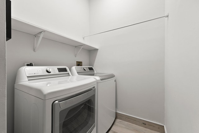 laundry area with light hardwood / wood-style floors and washing machine and clothes dryer