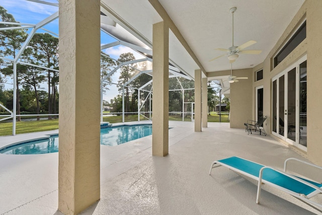 view of swimming pool featuring a patio, glass enclosure, and ceiling fan