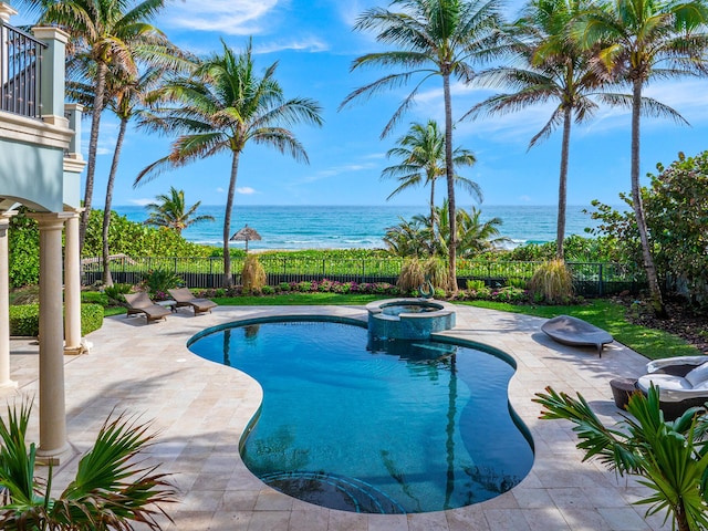 view of pool with a patio area, a water view, and an in ground hot tub