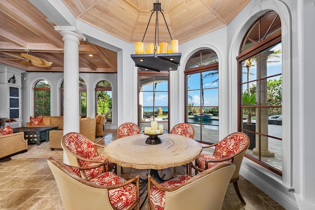 dining room with wooden ceiling, decorative columns, and a water view