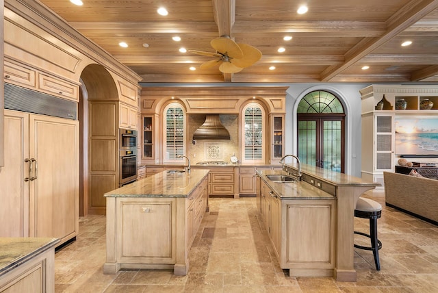 kitchen with a large island with sink, sink, light brown cabinetry, and wood ceiling