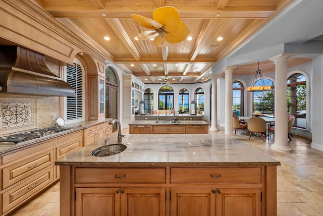 kitchen with a large island with sink, sink, wood ceiling, and ornate columns