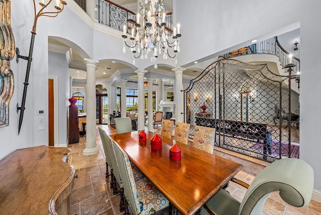 dining space with ornate columns, ornamental molding, a high ceiling, and a chandelier