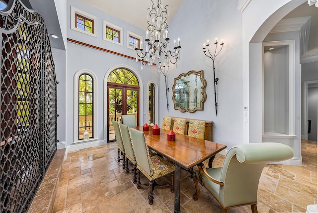 dining area featuring a towering ceiling, an inviting chandelier, and french doors