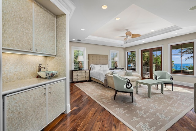 bedroom with dark wood-type flooring, a tray ceiling, sink, and french doors