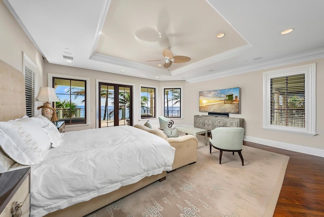 bedroom featuring french doors, crown molding, a tray ceiling, hardwood / wood-style flooring, and ceiling fan