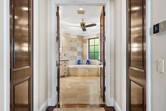 bathroom with tiled tub and ceiling fan