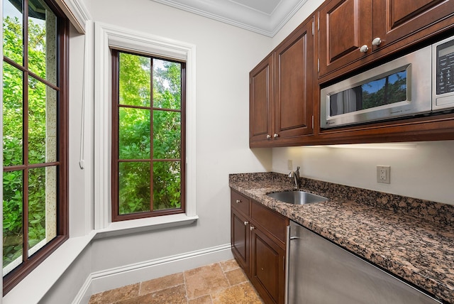 kitchen featuring dark stone countertops, sink, ornamental molding, and dark brown cabinetry