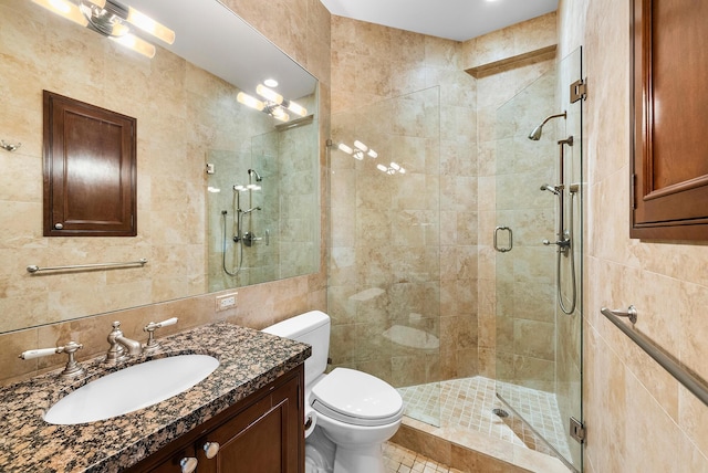 bathroom with tile walls, vanity, decorative backsplash, a shower with shower door, and toilet