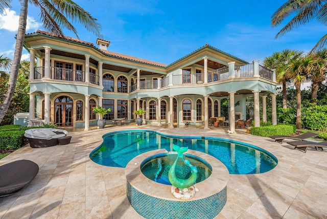 rear view of property featuring a swimming pool with hot tub, a patio, french doors, and a balcony