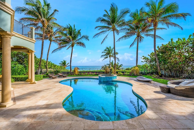 view of pool with a patio area, a water view, and an in ground hot tub