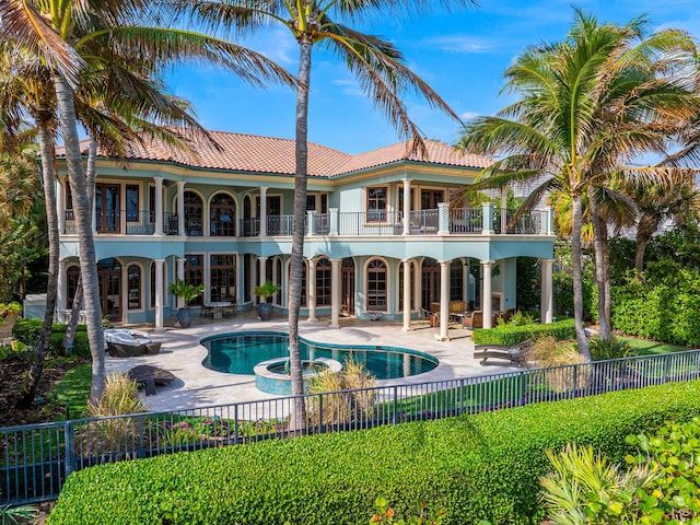 back of property featuring a pool with hot tub, a patio, and a balcony