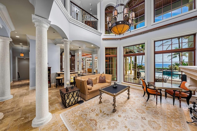 living room with decorative columns, ornamental molding, and a high ceiling