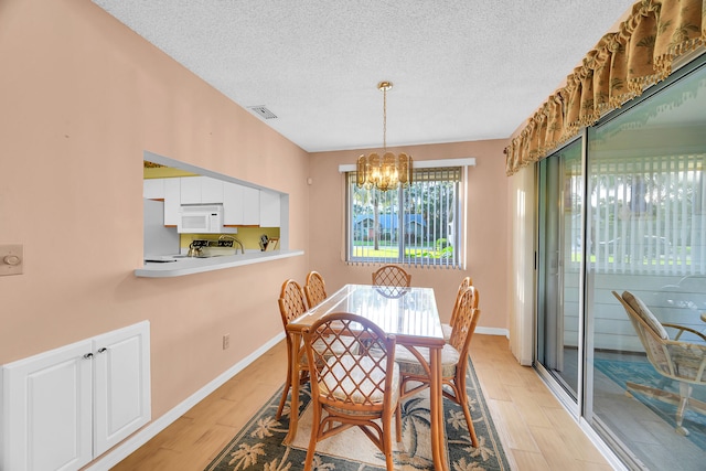 dining space featuring a notable chandelier, light hardwood / wood-style floors, and a textured ceiling