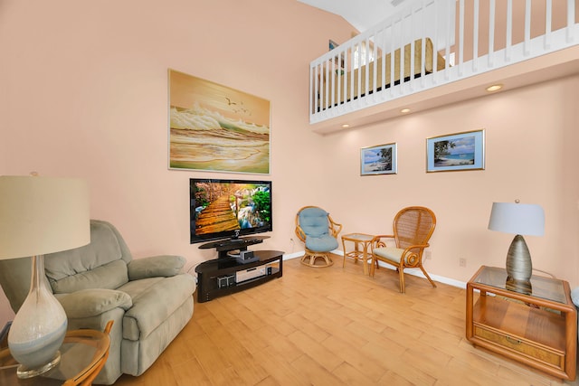 living room with a towering ceiling and light hardwood / wood-style flooring