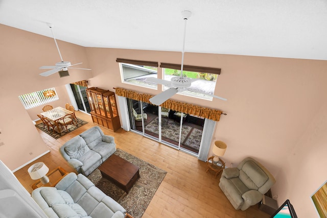 living room with hardwood / wood-style flooring, ceiling fan, and high vaulted ceiling