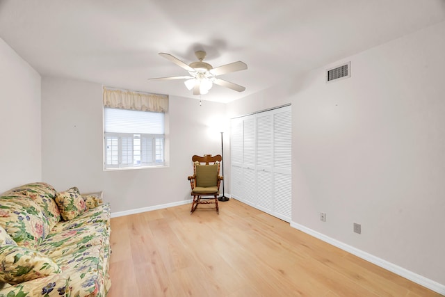 living area featuring wood-type flooring and ceiling fan