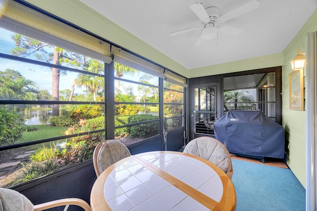 sunroom featuring ceiling fan and a water view