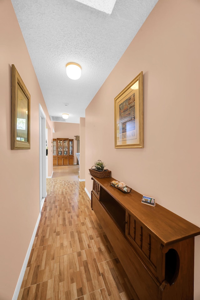 corridor featuring light hardwood / wood-style floors and a textured ceiling