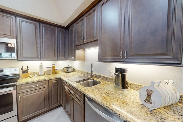 kitchen featuring light stone counters, sink, stainless steel appliances, and dark brown cabinets