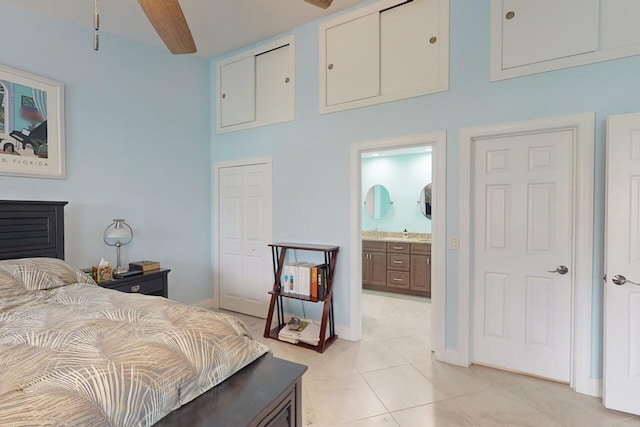 bedroom featuring beam ceiling, ensuite bathroom, light tile patterned floors, and ceiling fan