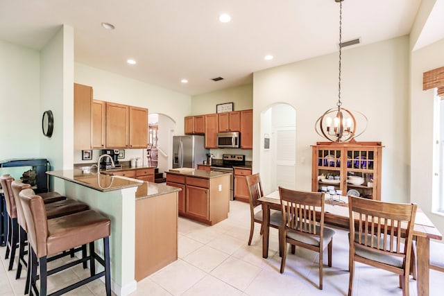 kitchen featuring kitchen peninsula, appliances with stainless steel finishes, a kitchen breakfast bar, a chandelier, and hanging light fixtures