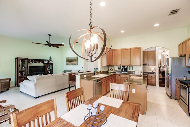 kitchen with kitchen peninsula, appliances with stainless steel finishes, ceiling fan with notable chandelier, sink, and hanging light fixtures