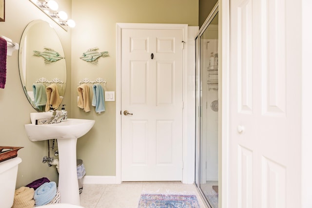 bathroom featuring tile patterned flooring, toilet, and an enclosed shower